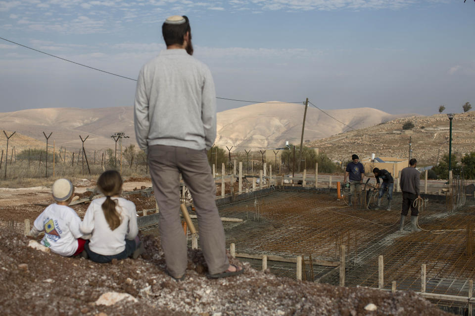 Jewish settler family members look at a construction of a new house at Gitit settlement in the West Bank’s Jordan Valley, Thursday, Jan. 2, 2014. A senior Israeli Cabinet minister and more than a dozen hawkish legislators poured cement at a construction site in a settlement in the West Bank's Jordan Valley on Thursday, in what they said was a message to visiting U.S. Secretary of State John Kerry that Israel will never relinquish the strategic area. (AP Photo/Oded Balilty)