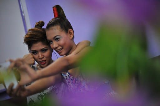 Me N Ma Girls band members take a picture of themselves with a smart phone as they prepare at a beauty salon ahead of a concert at a hotel in Yangon