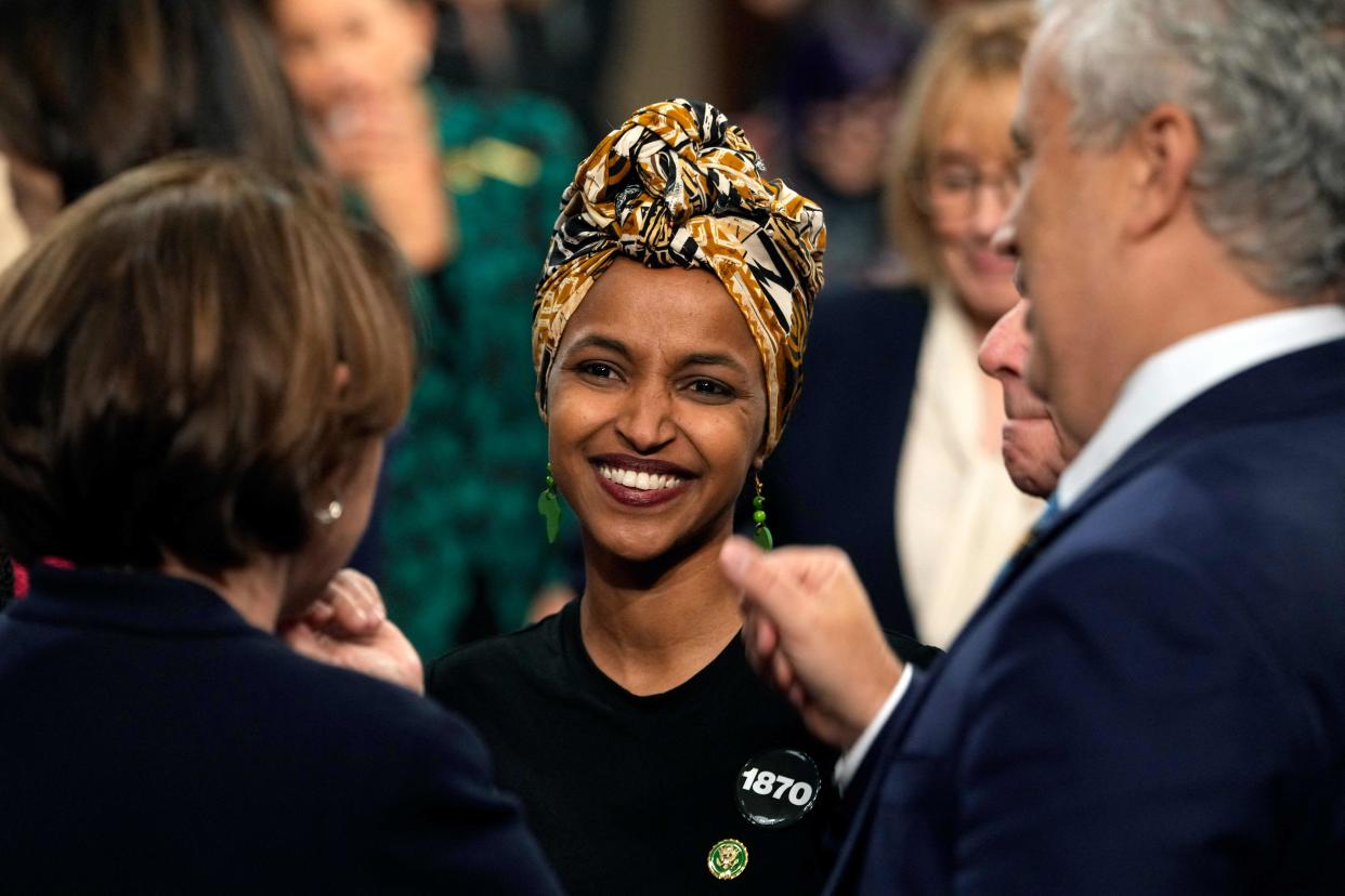 Rep. Ilhan Omar, in a colorful print headscarf, laughs at a colleague's remark.
