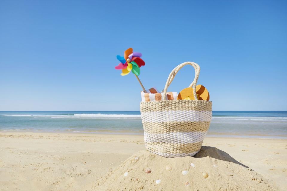 still life of beach bag and colorful pinwheel at sea against blue sky