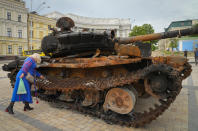 A woman looks at a destroyed Russian tank installed as a symbol of war in central Kyiv, Ukraine, Friday, May 20, 2022. (AP Photo/Efrem Lukatsky)