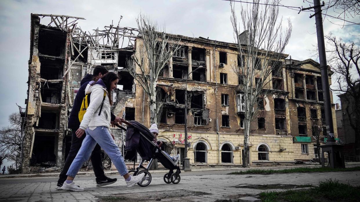 A couple walks past a damaged building in the Azov Sea port city of Mariupol, southeastern Ukraine (AFP via Getty Images)