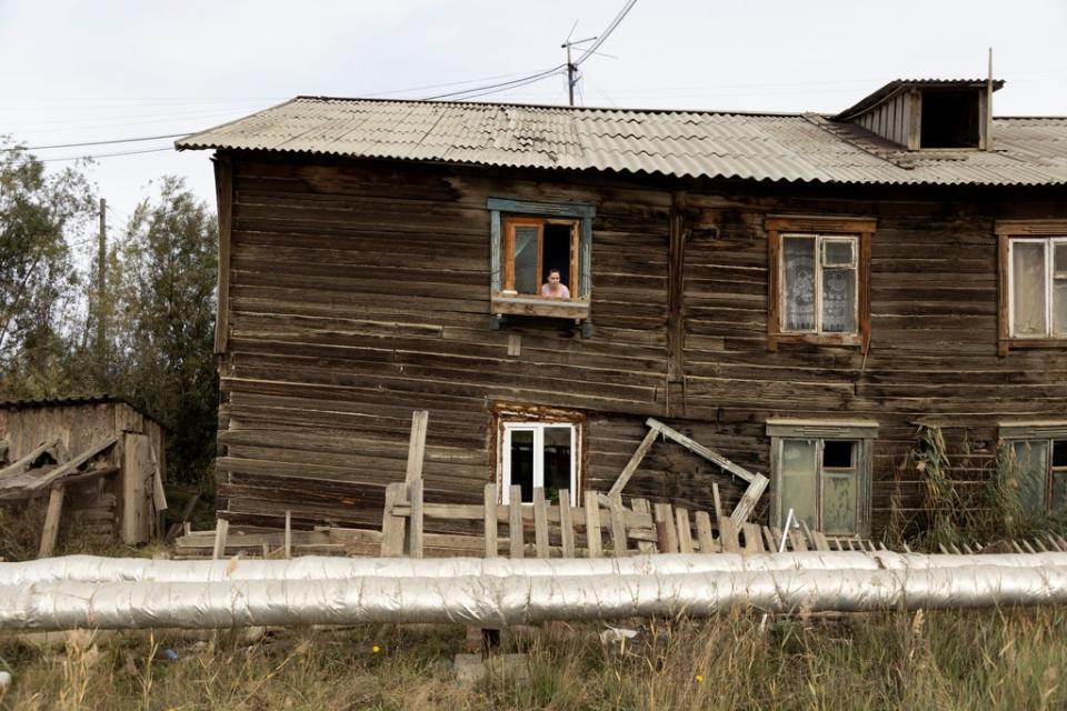 Maria Nedostupenko looks out of the window at her home which was damaged  by permafrost under its foundation (Reuters)