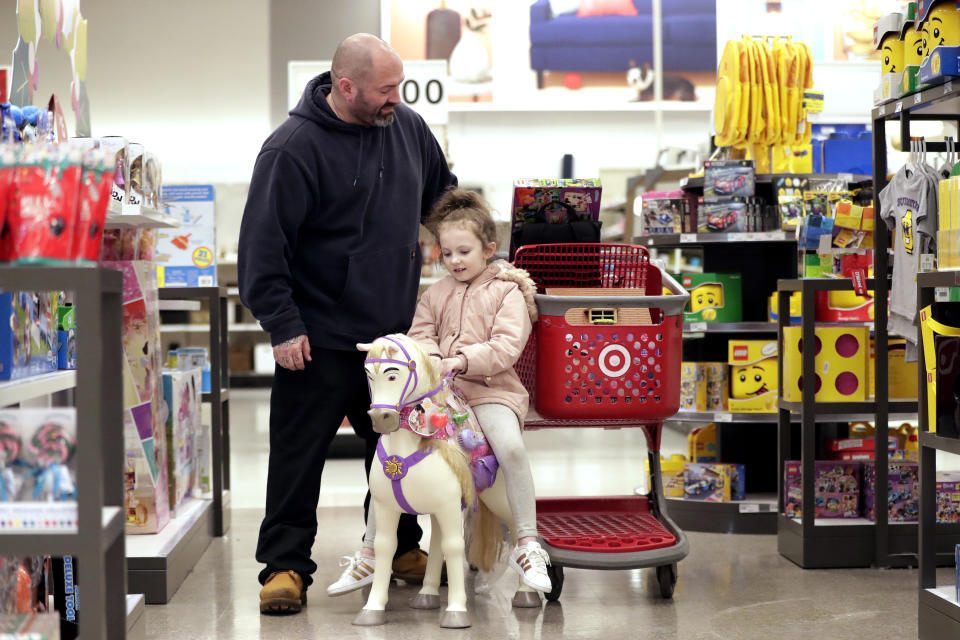 In this Friday, Nov. 16, 2018, photo James Deakyne, left, looks at items in his cart as his 7-year-old daughter, Madison, sits on a toy horse during a trip to get toys for her birthday at a Target store in Edison, N.J. Companies from Target to online mattress company Casper aren’t just counting on a stronger economy to pump up sales. Target’s CEO Brian Cornell estimated last month there’s up to $100 billion in market share for grabs, double what he foresaw just a year ago. So Target is accelerating its store remodels in areas where bankrupt retailers had stores. (AP Photo/Julio Cortez)