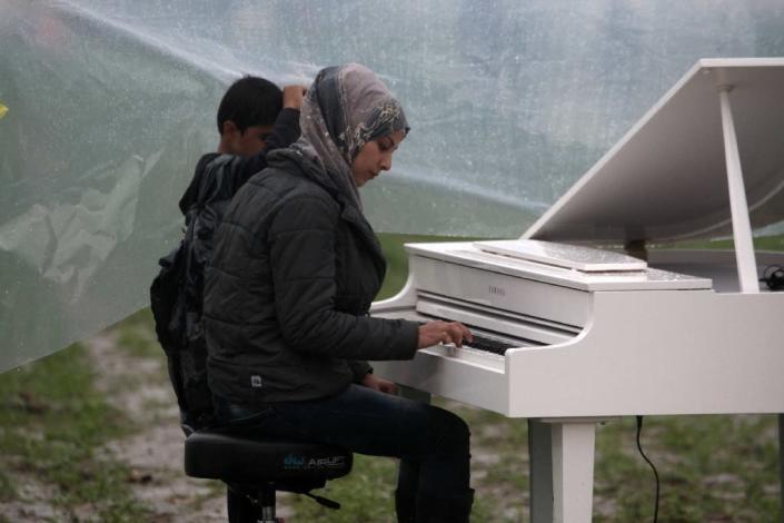 Syrian Nour Alkhzam, 24, plays the piano during a concert organized by Chinese artist Ai Weiwei at the Greek-Macedonian border near the Greek village of Idomeni, on March 12, 2016 (AFP Photo/Sakis Mitrolidis)