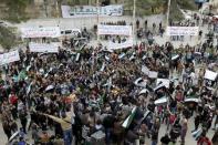 Protestors carry Free Syrian Army flags and chant slogans during an anti-government protest in the town of Marat Numan in Idlib province, Syria March 4, 2016. The text on the banners read in Arabic "Together we renew our pledge of allegiance, curse your soul Hafez" (top R), "Wherever you head to, we will go to the squares and the fronts" (top C) and "Before the people, you have no choice but to leave" (top L). REUTERS/Khalil Ashawi