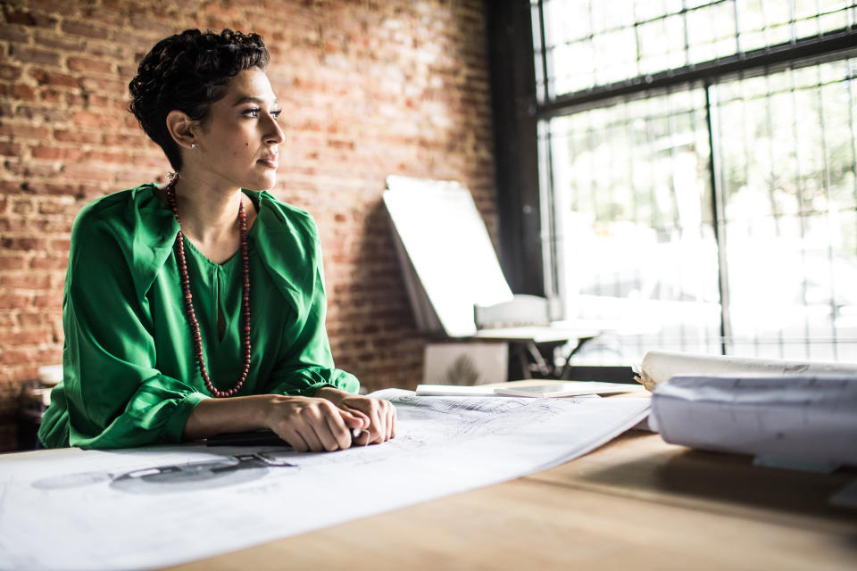 Portrait of Businesswoman looking over architecture blueprints in office