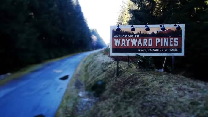 A billboard for Wayward Pines on the side of the road in "Wayward Pines"