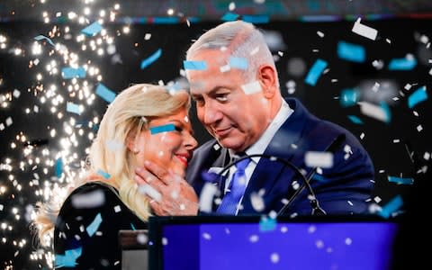 Israeli Prime Minister Benjamin Netanyahu embraces his wife Sara as confetti and fireworks are blown during his appearance before supporters at his Likud Party headquarters in the Israeli coastal city of Tel Aviv on election night early on April 10, 2019.  - Credit: AFP
