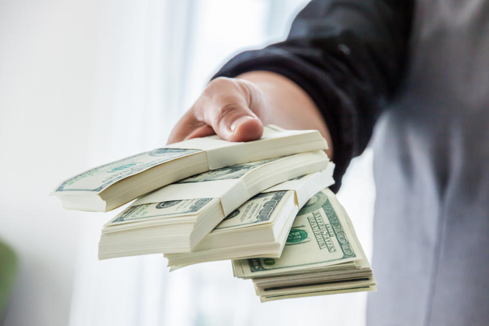 An outstretched hand holding stacks of American $100 bills