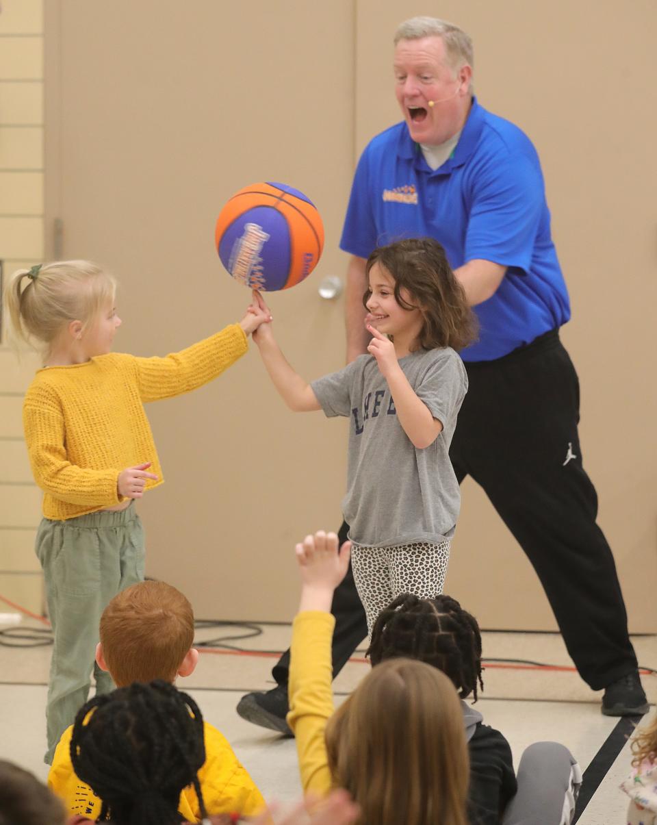 Jude Michael, left, and Ellie Rich hold a spinning basketball on their finger during a performance with Jim "Basketball" Jones at Herberich Primary School on Tuesday in Fairlawn.