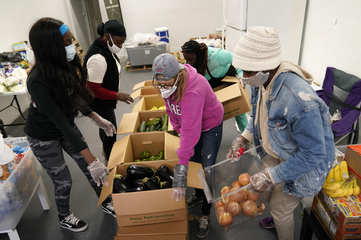 Sherina Jones, left, works with volunteers organizing food for distribution, Wednesday, Dec. 9, 2020, in the Liberty City neighborhood of Miami. (AP Photo/Lynne Sladky)