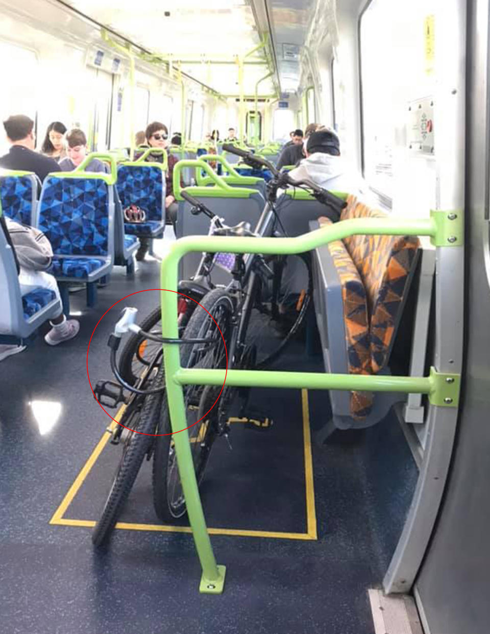 Two bikes on a Melbourne train locked into place in front of an empty disable seat.