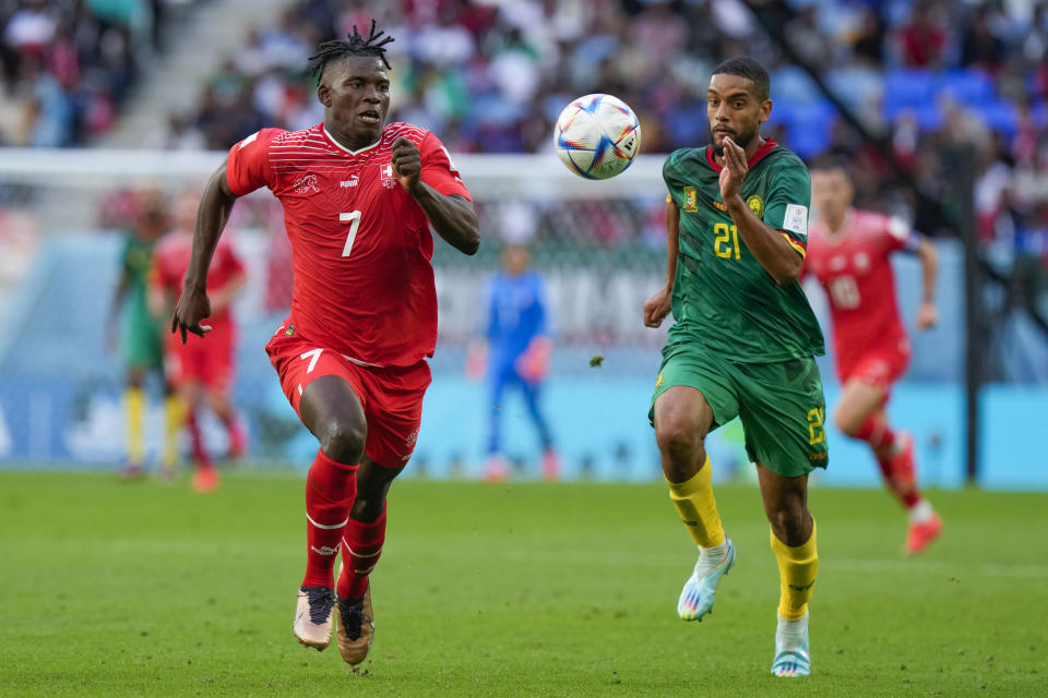 Breel Embolo (izquierda), de Suiza, corre detrás del balón con el camerunés Jean-Charles Castelletto durante el juego del Grupo G que enfrentó a ambas naciones, en el estadio Al Janoub, en Al Wakrah, Qatar, el 24 de noviembre de 2022. (AP Foto/Luca Bruno)