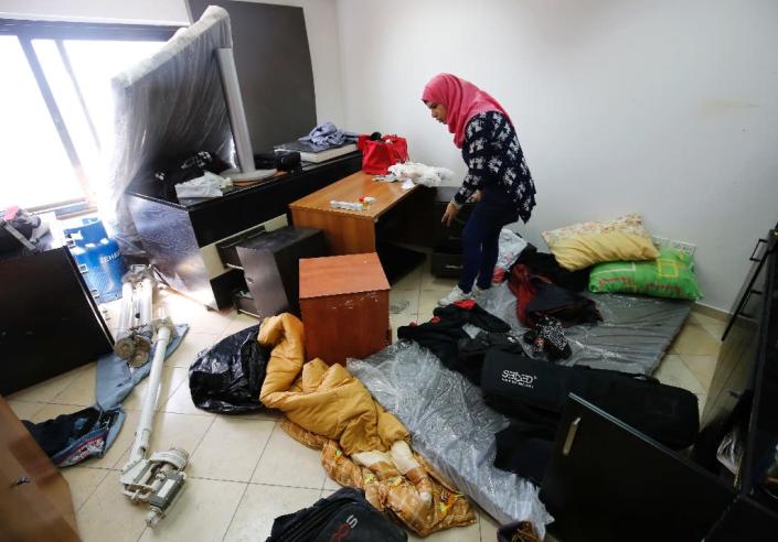 A Palestinian woman inspects the damage at the Palestine Today television offices after it had been raided by Israeli forces overnight on March 11, 2016, in the West Bank city of Ramallah (AFP Photo/Abbas Momani)