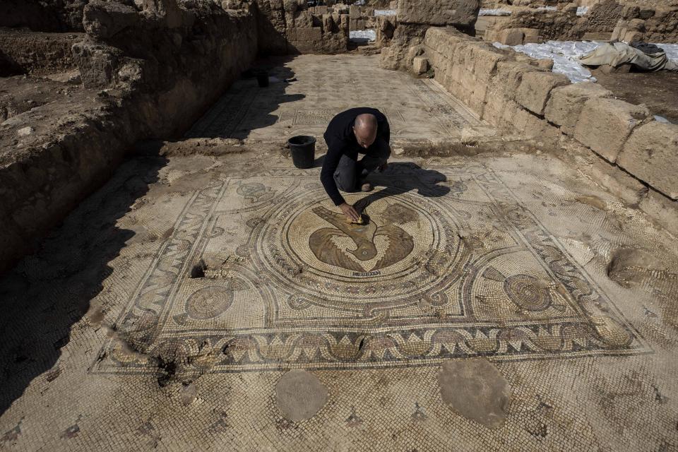 An Israeli preservative Shmulik Freireich, from the Israel Antiquities Authority, shows a mosaic depicting an eagle in an ancient church that was recently uncovered in Beit Shemesh, near Jerusalem. Wednesday, Oct. 23, 2019. Israeli archaeologists have revealed an elaborately decorated Byzantine church dedicated to an anonymous martyr that was recently uncovered near Jerusalem. The Israel Antiquities Authority showcased some of the finds from the nearly 1,500-year-old structure on Wednesday after three years of excavations. (AP Photo/Tsafrir Abayov)