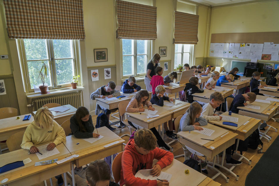 A teacher helps students practice their handwriting at the Djurgardsskolan elementary school in Stockholm, Sweden, Thursday, Aug. 31, 2023. As children across Sweden have recently flocked back to school after the summer vacation, many of their teachers are putting a new emphasis on printed books, quiet reading hours, and practicing handwriting as the country's yearslong focus on the digitalization of classrooms has come under scrutiny. (AP Photo/David Keyton)