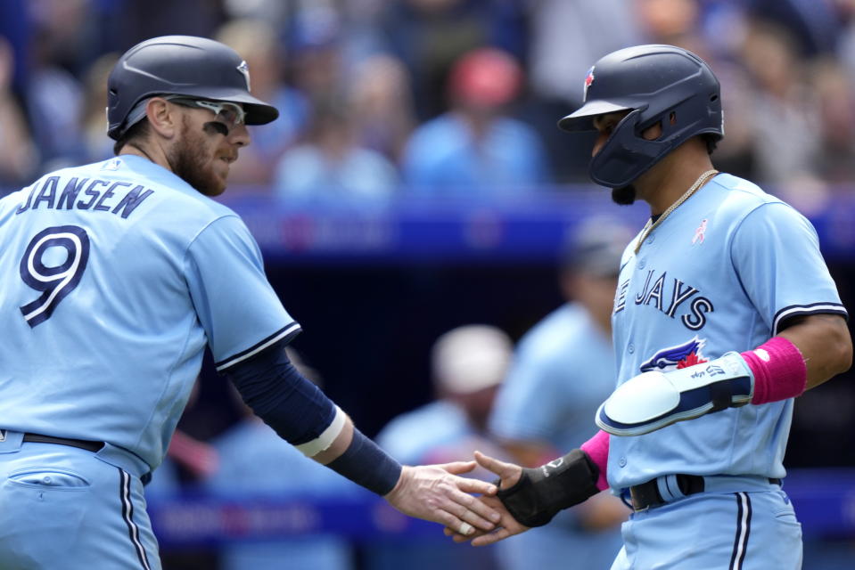 Toronto Blue Jays' Danny Jansen (9) and Santiago Espinal celebrate after scoring during the second inning of a baseball game against the Atlanta Braves in Toronto, on Sunday, May 14, 2023. (Frank Gunn/The Canadian Press via AP)