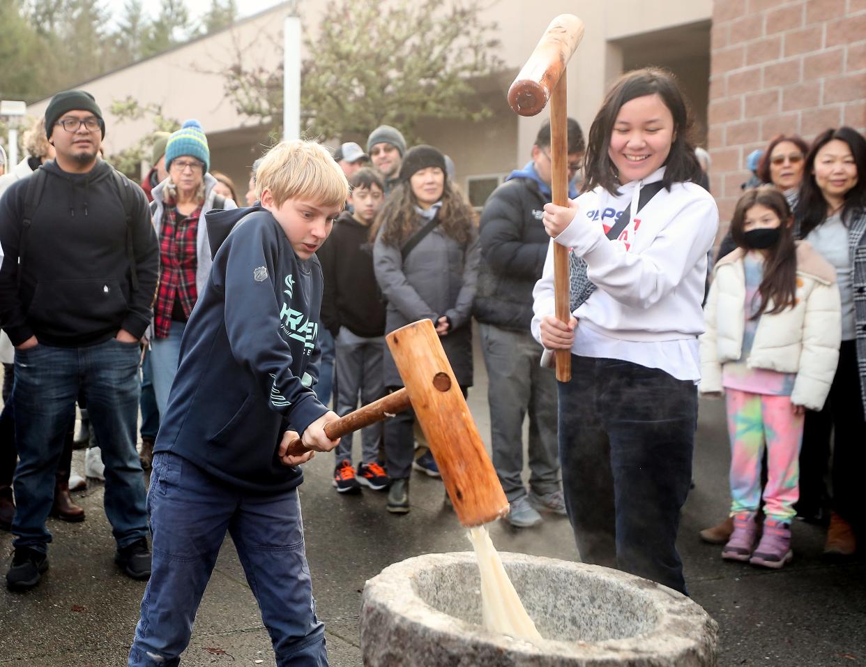The steamed sweet rice sticks to 10-year-old Luke Meidell’s cherry wood mallet as he and Alayna Hatch, 11, help pound the rice in the granite bowl to make mochi during Mochi Tsuki at Bainbridge Island’s Woodward Middle School on Saturday, Jan. 6, 2024.
