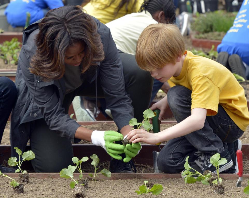 First lady Michelle Obama and Bancroft Elementary School student Silas Stutz, right, plant broccoli in the White House Kitchen Garden at the White House in Washington, Wednesday, April 2, 2014. (AP Photo/Susan Walsh)