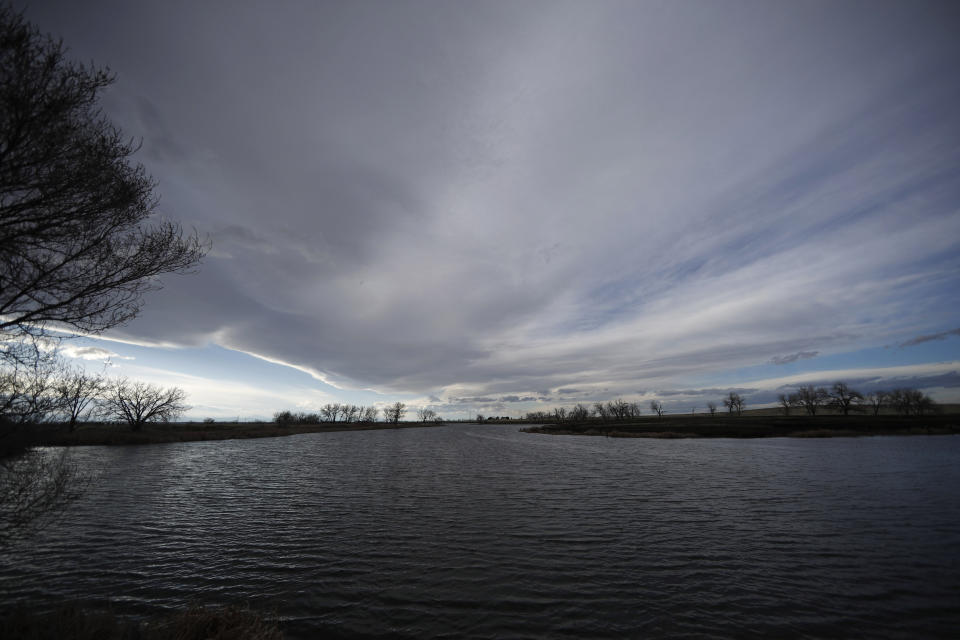 FILE - In this Sunday, April 14, 2019 file photo, clouds loom over a lake at the Rocky Mountain Arsenal National Wildlife Refuge Sunday, April 14, 2019, in Commerce City, Colo. Critics say Rocky Mountain Arsenal in Colorado illustrates the shortcomings of a cleanup designed to be good enough for a refuge but not for human habitation. (AP Photo/David Zalubowski)