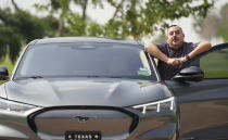 Jose Valdez, 45, who owns three EVs, poses with his Mustang Mach-E, Thursday, May 9, 2024, in San Antonio. Many Americans still aren’t sold on going electric for their next car purchase. High prices and a lack of easy-to-find charging stations are major sticking points, a new poll shows. Valdez owns three EVs, including a new Mustang Mach-E. With a tax credit and other incentives, the sleek new car cost about $49,000, Valdez said. He thinks it's well worth the money. (AP Photo/Eric Gay)