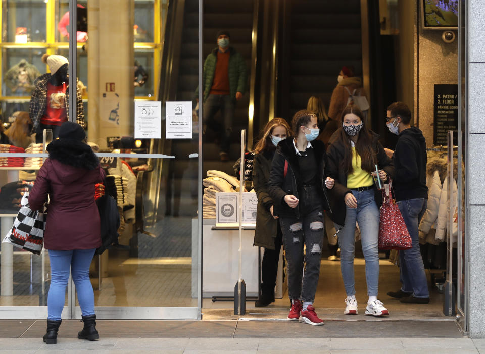 People leave a store in Prague, Czech Republic, Thursday, Dec. 3, 2020. A sign of normalcy has returned to the Czech Republic ahead of the Christmas period after the government eased some of its most restrictive measures imposed to contain the recent massive surge of coronavirus infections. On Thursday all stores, shopping malls, restaurants, bars and hotels were allowed to reopen. (AP Photo/Petr David Josek)