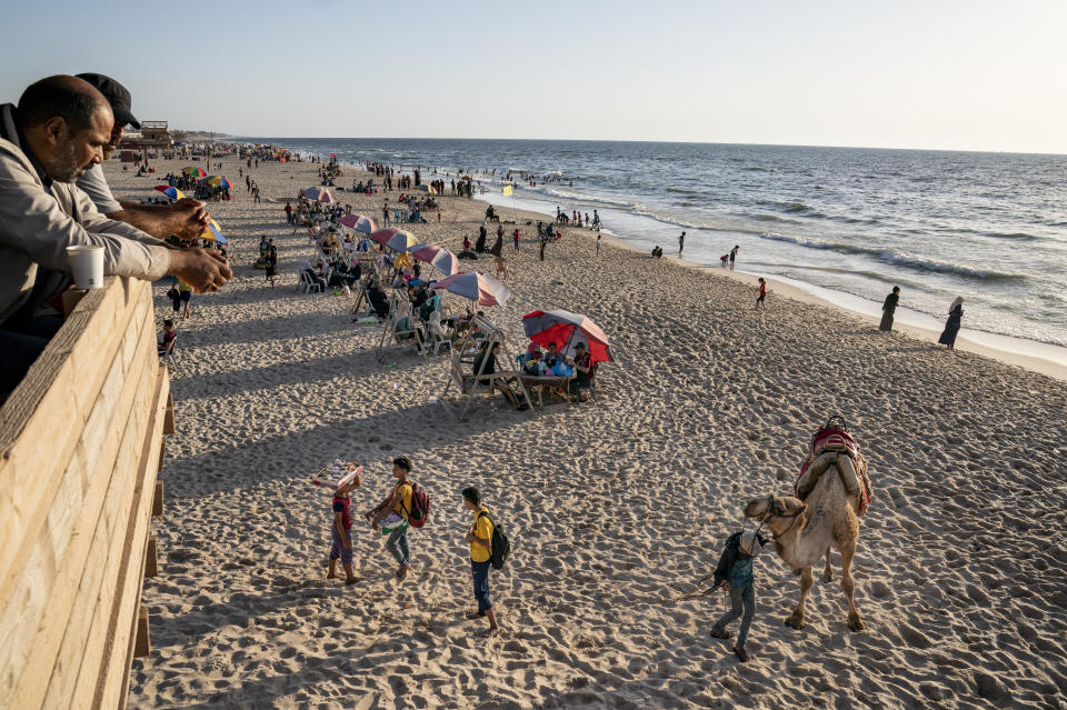 A man offer camel rides to customers on the shores of the Mediterranean Sea, as life begins to return to a semblance of normal, days after the end of an 11-day war between Gaza's Hamas rulers and Israel, Tuesday, May 25, 2021, in Gaza City. (AP Photo/John Minchillo)