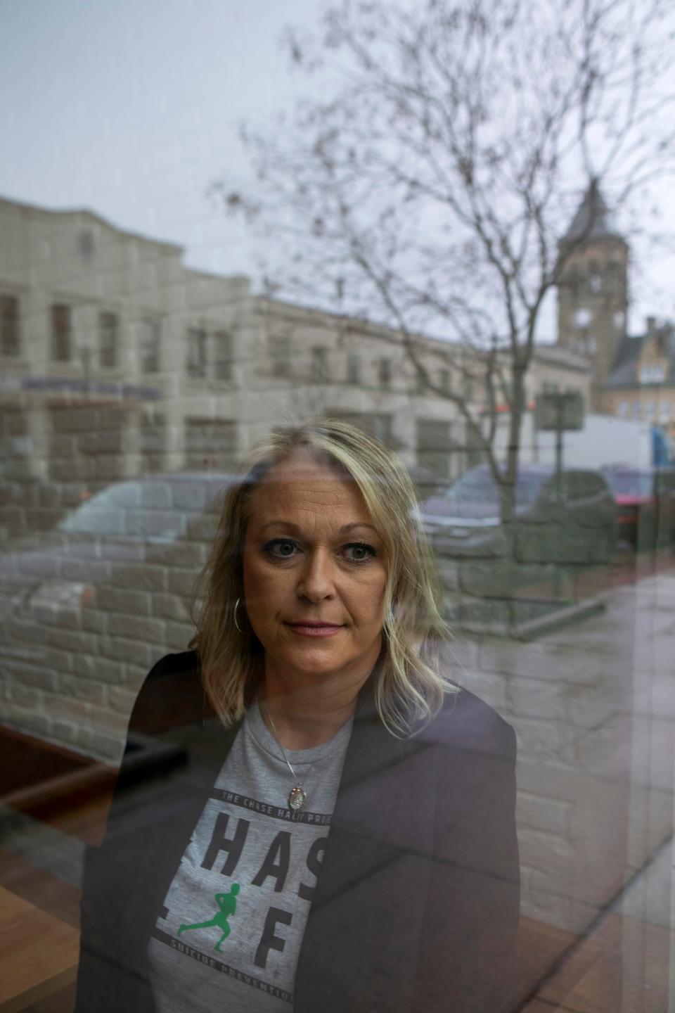 Sarah Haley looks out of the window, as the reflection of downtown Lancaster is caught in the reflection, on Mar. 6, 2024, in Lancaster, Ohio. Sarah started the Chase Haley Project, which is a support and education group, after her son died by suicide in 2022.