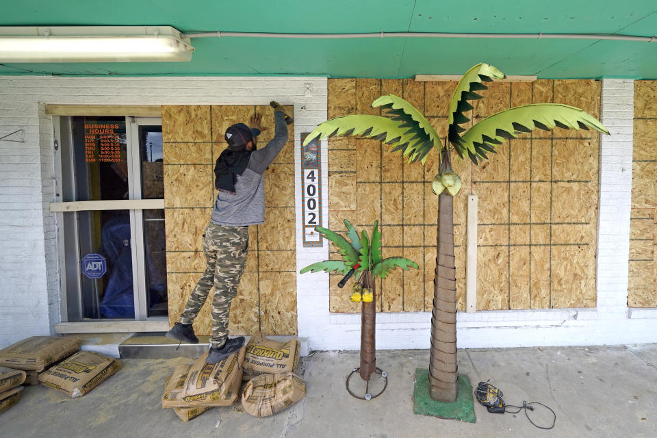 Issac Alvarado boards up windows of coastal decor store Bayside Chic, Tuesday, Aug. 25, 2020, in Galveston, Texas, as Hurricane Laura heads toward the Gulf Coast. (AP Photo/David J. Phillip)