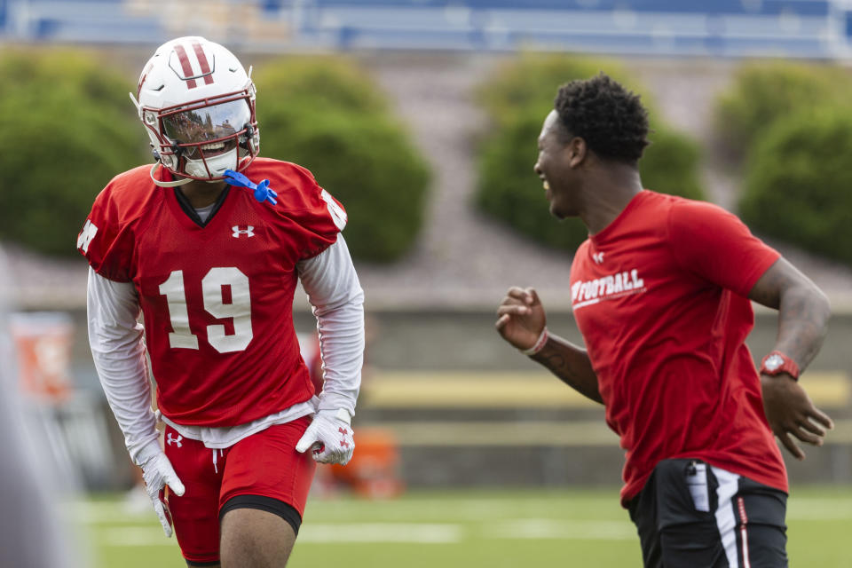 Wisconsin NCAA college football wide receiver Will Pauling (19) smiles at D.J. Stubbs, offensive graduate assistant, on the first day of training camp in Platteville, Wisc., Wednesday, Aug. 2, 2023. (Samantha Madar/Wisconsin State Journal via AP)