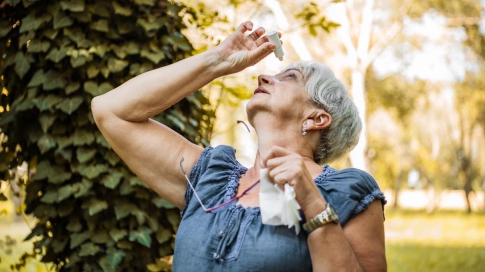A mature woman outdoors applying eye drops as part of her conjunctivitis self-care strategy