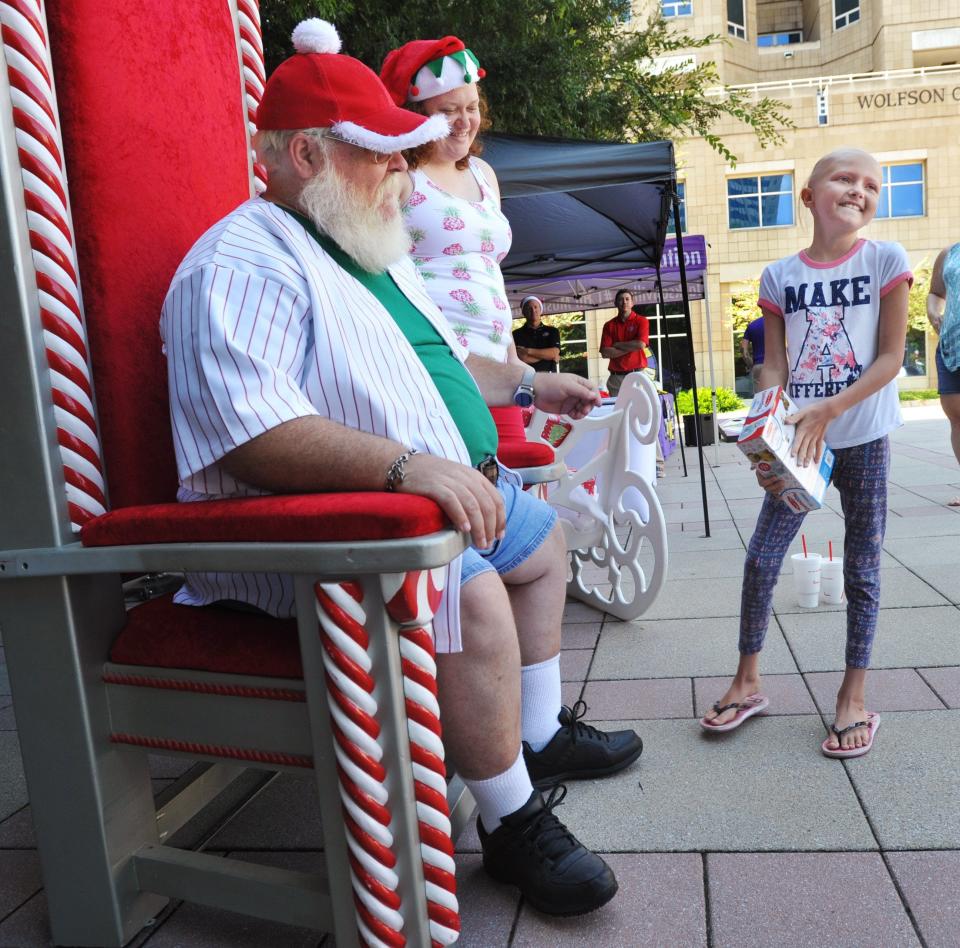 Christmas in July for a good cause: "Santa John" Hucks (left) talks with patient Jordan Elliott, 10, after giving her a toy during the 2018 Christmas in July toy donation and drive at Wolfson Children's Hospital and Baptist Health in Jacksonville.
