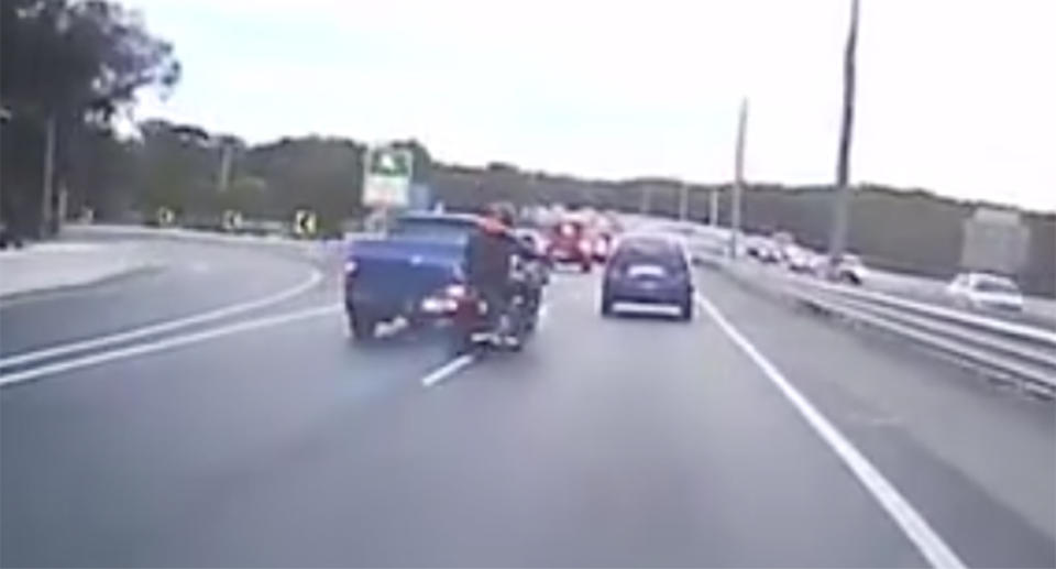 Dashcam Owners Australia footage shows the moment a motorcyclist is nudged off his bike on the Gateway Motorway, Brisbane.