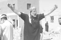 An Iraqi shouts his anger over the grave of his son, buried in a soccer field turned into a cemetery in Fallujah, Iraq, during the war.