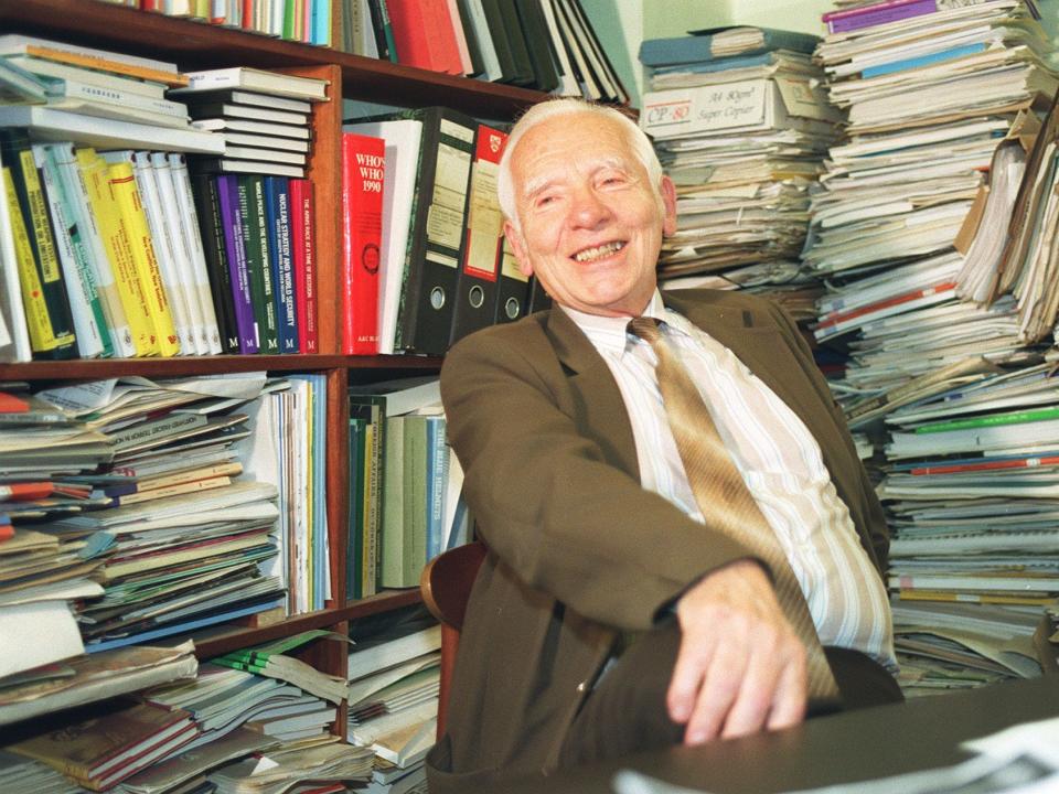 Nobel Peace Prize winner Joseph Rotblat surrounded by books and papers while wearing a suit in 1995