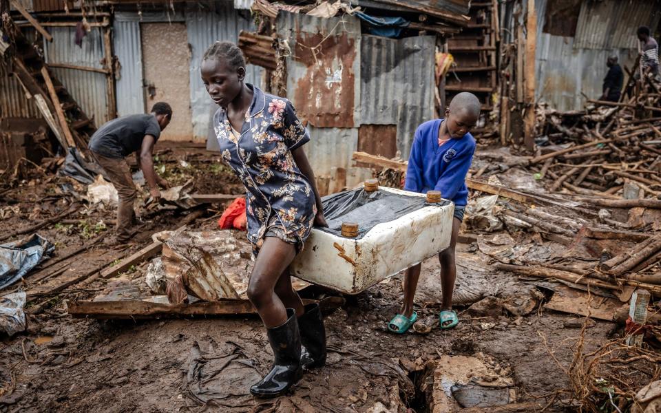 A girl and a boy carry a piece of furniture after visiting their house that was destroyed by floods following torrential rains at the Mathare informal settlement in Nairobi