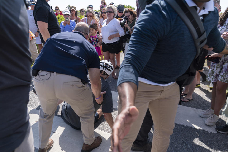 President Joe Biden is helped by U.S. Secret Service agents after he fell trying to get off his bike to greet a crowd on a trail at Gordons Pond in Rehoboth Beach, Del., Saturday, June 18, 2022. (AP Photo/Manuel Balce Ceneta)