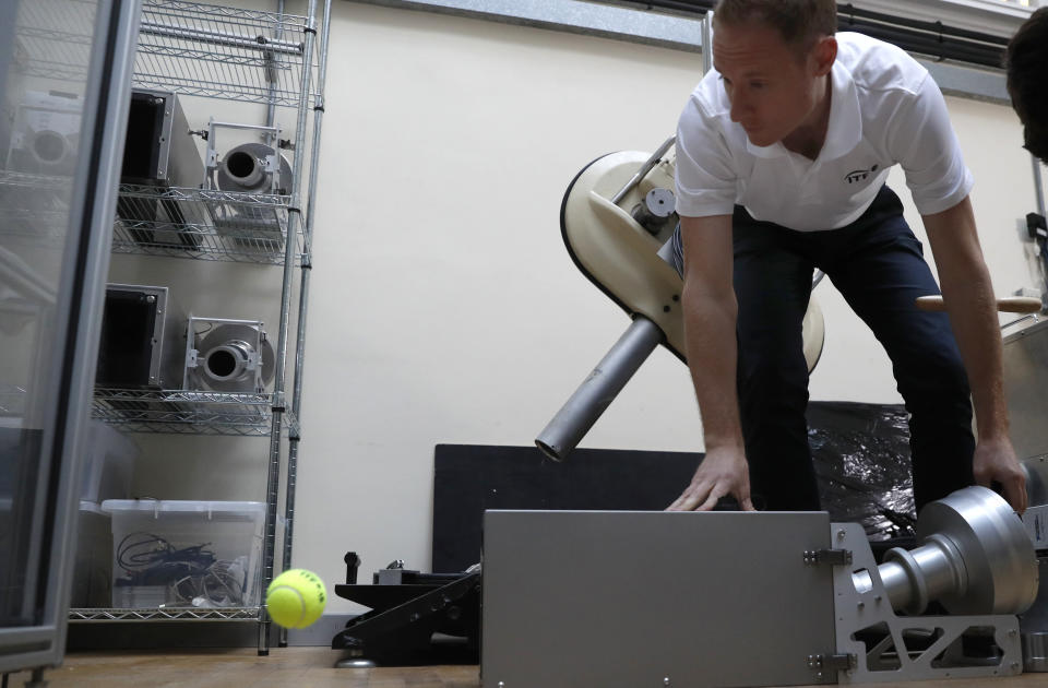 In this photo taken Friday June, 28, 2019, Jamie Caple-Davies, the head of the International Tennis Federation science and technical department, shows off a machine that tests the surface of a tennis court, during an interview with the Associated Press, at the International Tennis Federation (ITF) lab in Roehampton, near Wimbledon south west London. Based for about 20 years in a three-room area on what used to be a pair of squash courts in Roehampton, the ITF tech lab is filled with more than $1 million worth of machines that help make sure rules are followed and parameters are met. (AP Photo/Alastair Grant)