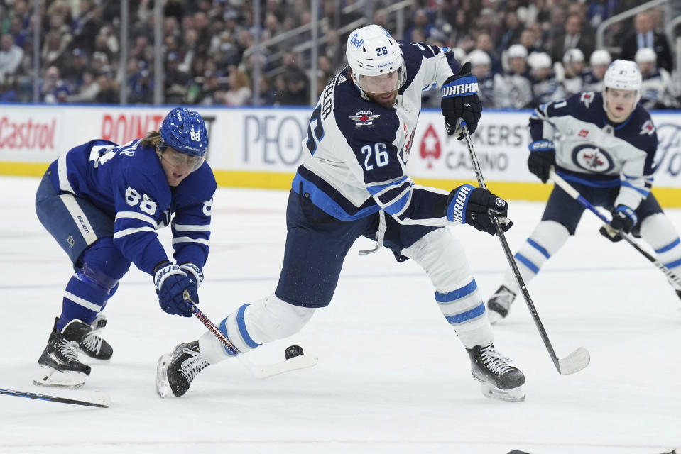 FILE - Winnipeg Jets right wing Blake Wheeler (26) tries to controls the puck as Toronto Maple Leafs right wing William Nylander (88) defends during the first period of an NHL hockey game, Thursday, Jan. 19, 2023 in Toronto. A handful of teams spent the eve of free agency clearing salary cap space with big money buyouts. The Winnipeg Jets put former captain Blake Wheeler on unconditional waivers to buy out the final year of his contract. (Nathan Denette/The Canadian Press via AP, File)