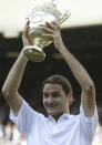 FILE - Roger Federer holds the trophy after defeating Andy Roddick in the Men's Singles final on the Centre Court at Wimbledon, Sunday July 4, 2004. Federer won the match 4-6, 7-5, 7-6 (3), 6-4, to retain the title. Caulkin, a retired Associated Press photographer has died. He was 77 and suffered from cancer. Known for being in the right place at the right time with the right lens, the London-based Caulkin covered everything from the conflict in Northern Ireland to the Rolling Stones and Britain’s royal family during a career that spanned four decades. (AP Photo/Dave Caulkin, File)