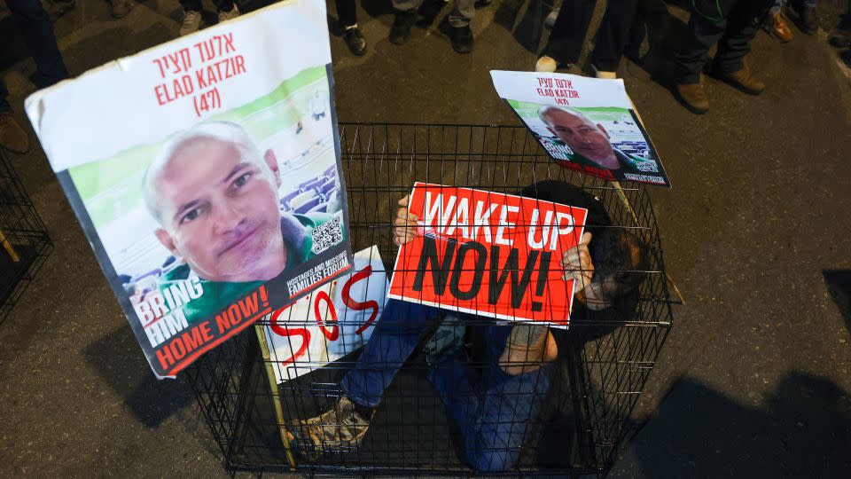 A man sits in a cage with portraits of 47-year-old Israeli hostage Elad Katzir, in Tel Aviv, Israel on March 26, 2024. - Jack Guez/AFP/Getty Images