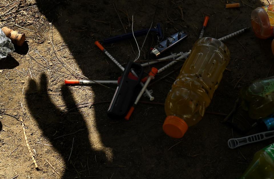 A shadow of a work crew member stands over syringes and other items.