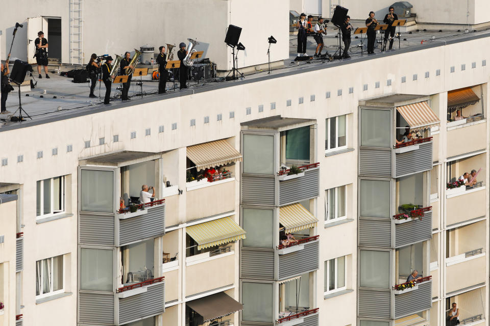 Residents on their balconies listen to a concert featuring distant harmonies, at a time when cultural events have been disrupted by the coronavirus pandemic, in the Prohlis neighborhood in Dresden, Germany, Saturday, Sept. 12, 2020. About 33 musicians of the Dresden Sinfoniker perform a concert named the 'Himmel ueber Prohils', The Sky above Prohlis, on the roof-tops of communist-era apartment blocs in the Dresden neighborhood Prohlis. (AP Photo/Markus Schreiber)