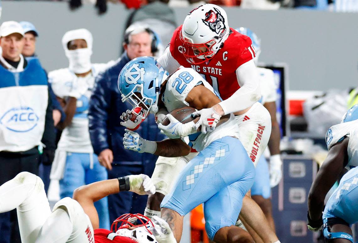 N.C. State linebacker Payton Wilson (11) tackles North Carolina running back Omarion Hampton (28) during the second half of N.C. State’s 39-20 victory over UNC at Carter-Finley Stadium in Raleigh, N.C., Saturday, Nov. 25, 2023. Ethan Hyman/ehyman@newsobserver.com