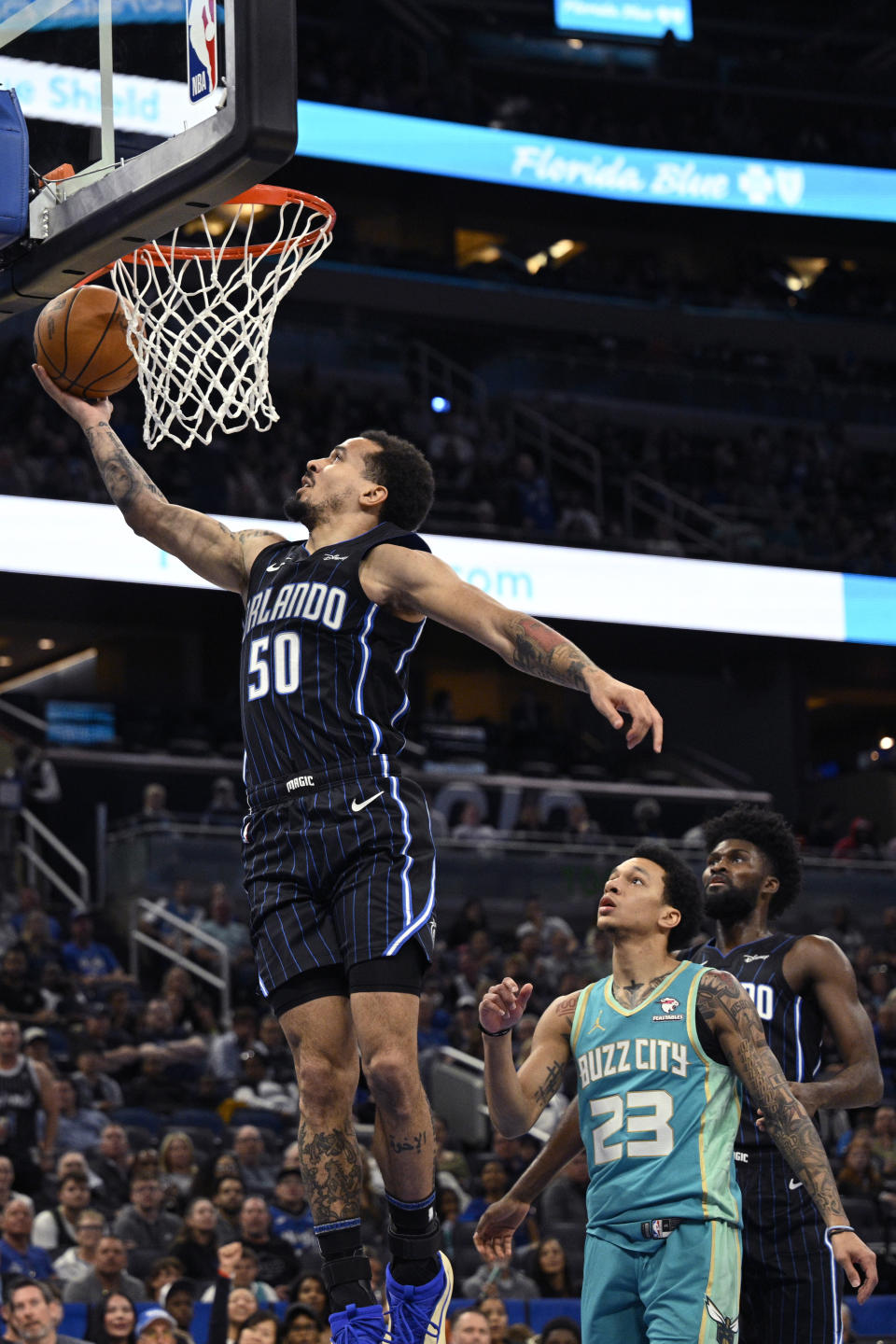 Orlando Magic guard Cole Anthony (50) goes up to shoot as forward Jonathan Isaac, right, and Charlotte Hornets guard Tre Mann (23) look on during the first half of an NBA basketball game, Tuesday, March 19, 2024, in Orlando, Fla. (AP Photo/Phelan M. Ebenhack)