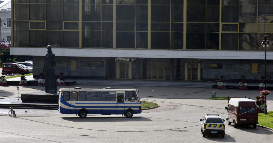 Two police cars stand by a bus containing hostages after an armed man seized a bus and took some 20 people hostage in the city centre of Lutsk, some 400 kilometers (250 miles) west of Kyiv, Ukraine on Tuesday July 21, 2020. The assailant is armed and carrying explosives, according to a Facebook statement by Ukrainian police. Police officers are trying to get in touch with the man and they have sealed off the area. (AP Photo/Pavlo Palamarchuk)