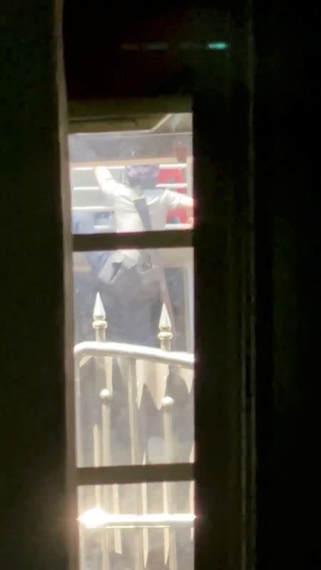 Armed security officer climbs over a gate before proceeding to the upper floor of a building, during crackdown in Bago