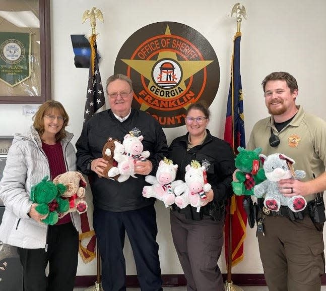 FILE - Franklin County Sheriff Steve Thomas, second from left, poses with others as they hold stuffed animals donated to his office to build rapport with children affected by a crisis.