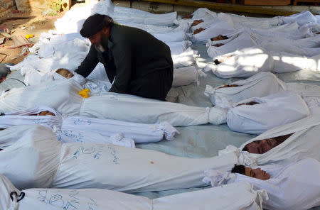 FILE PHOTO: A man holds the body of a dead child, among bodies of people activists say were killed by nerve gas, in the Ghouta region, in the Duma neighbourhood of Damascus, Syria August 21, 2013. REUTERS/Bassam Khabieh/File Photo